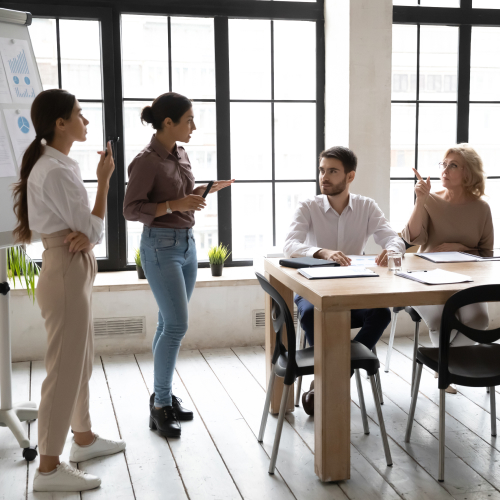 Scène de réunion dans un bureau lumineux, avec plusieurs personnes autour d’une table